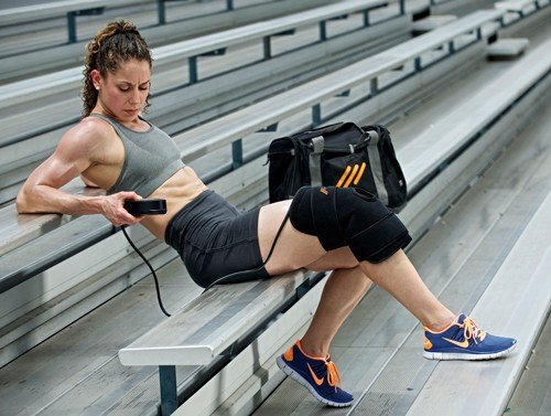 athlete sitting on bleachers using PowerPlay cold compression knee wrap