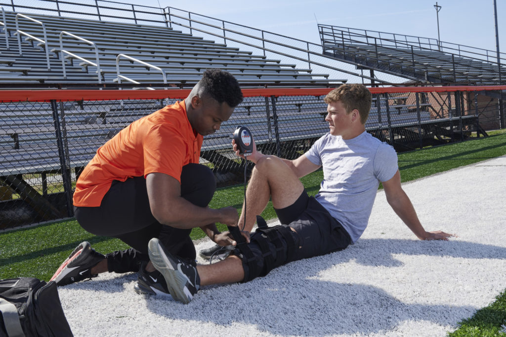 An athletic trainer helps his athlete apply cold compression therapy