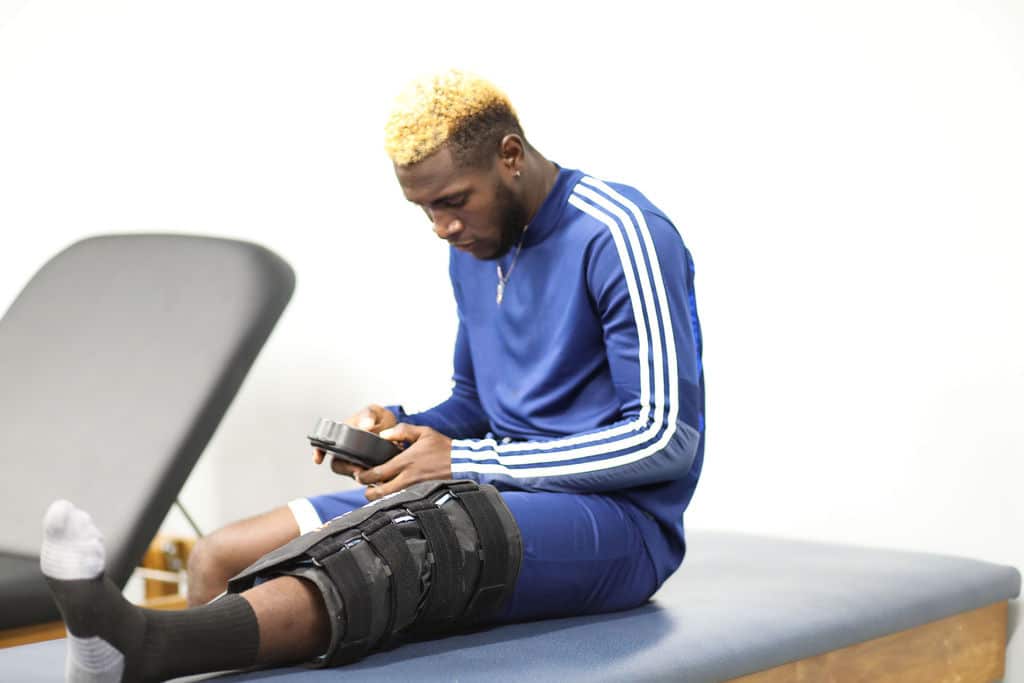 An athlete using a 360 Knee Wrap on a table in an athletic training room.