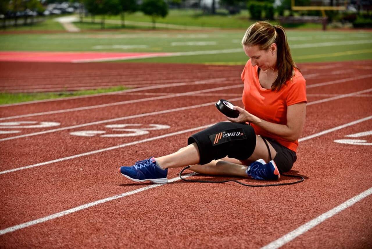 A woman using PowerPlay 360 Cold Compression Knee Wrap on Running Track