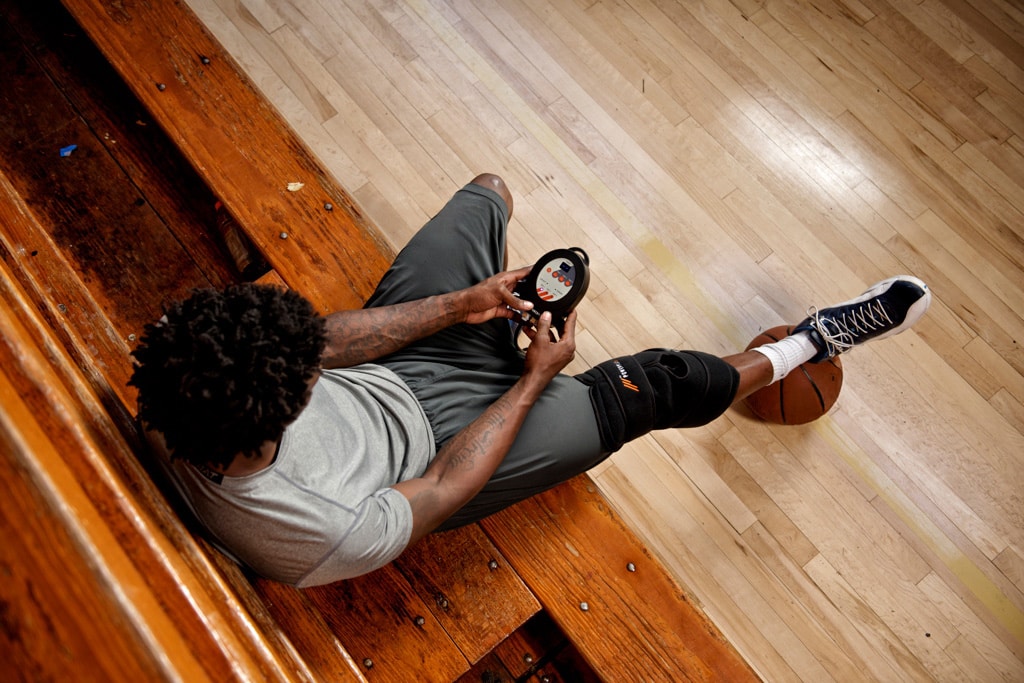 Basketball player using a standard PowerPlay cold compression knee wrap in a gym.